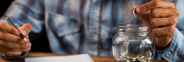 a person seen calculating expenses and saving the left money in a glass jar
